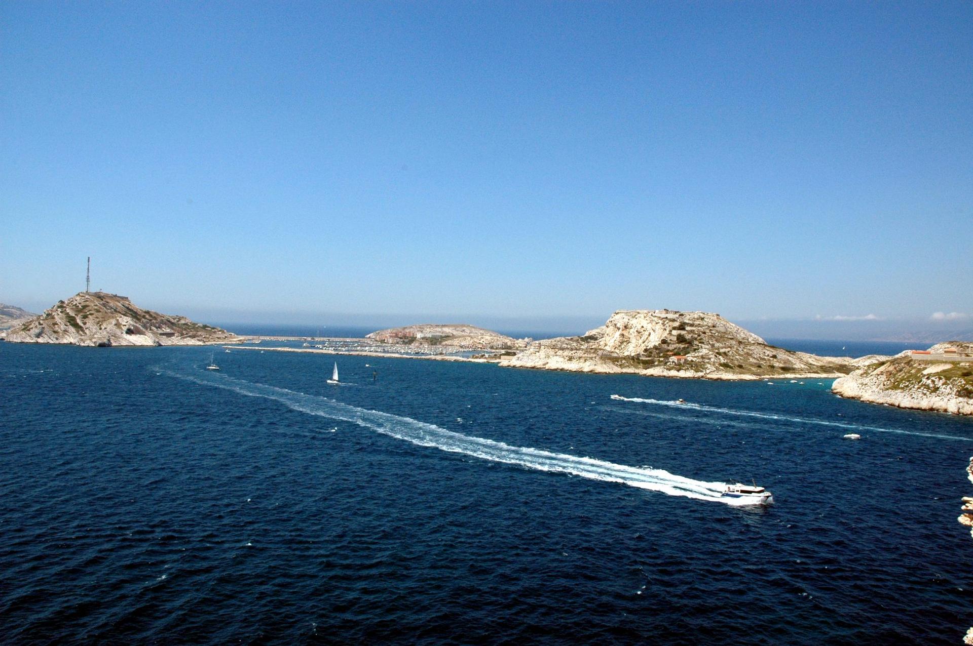 La rade et les îles, un bateau traçant son sillage sur une mer bleu profond